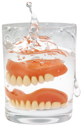 Dentures being dropped into a glass of water